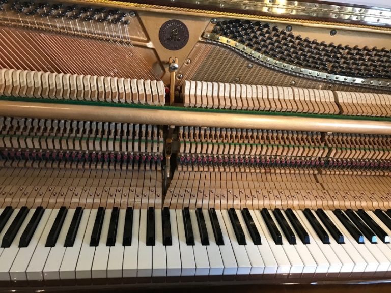 Upright piano with the front panel removed showing the hammers, dampers and keys