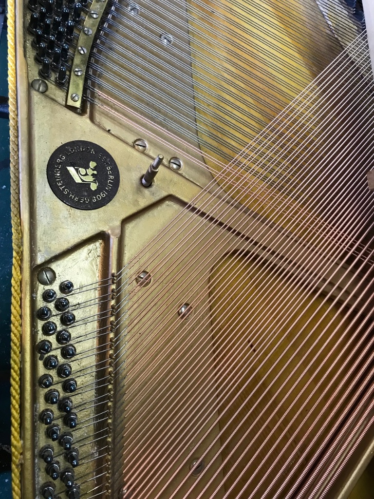 Newly restrung copper wound bass strings inside a restored grand piano