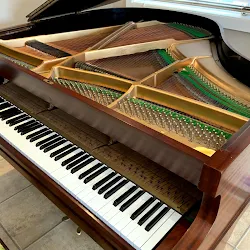 Fully restored baby grand piano with the lid open showing the strings and keys