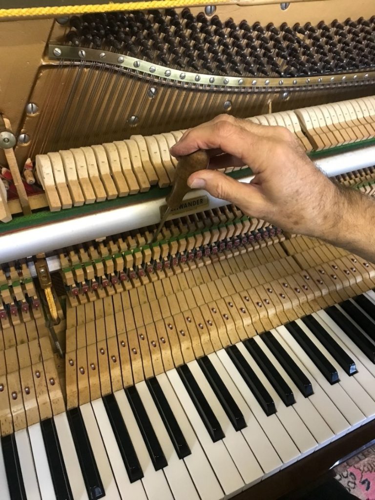 David Cremer voicing the hammers inside an upright piano action