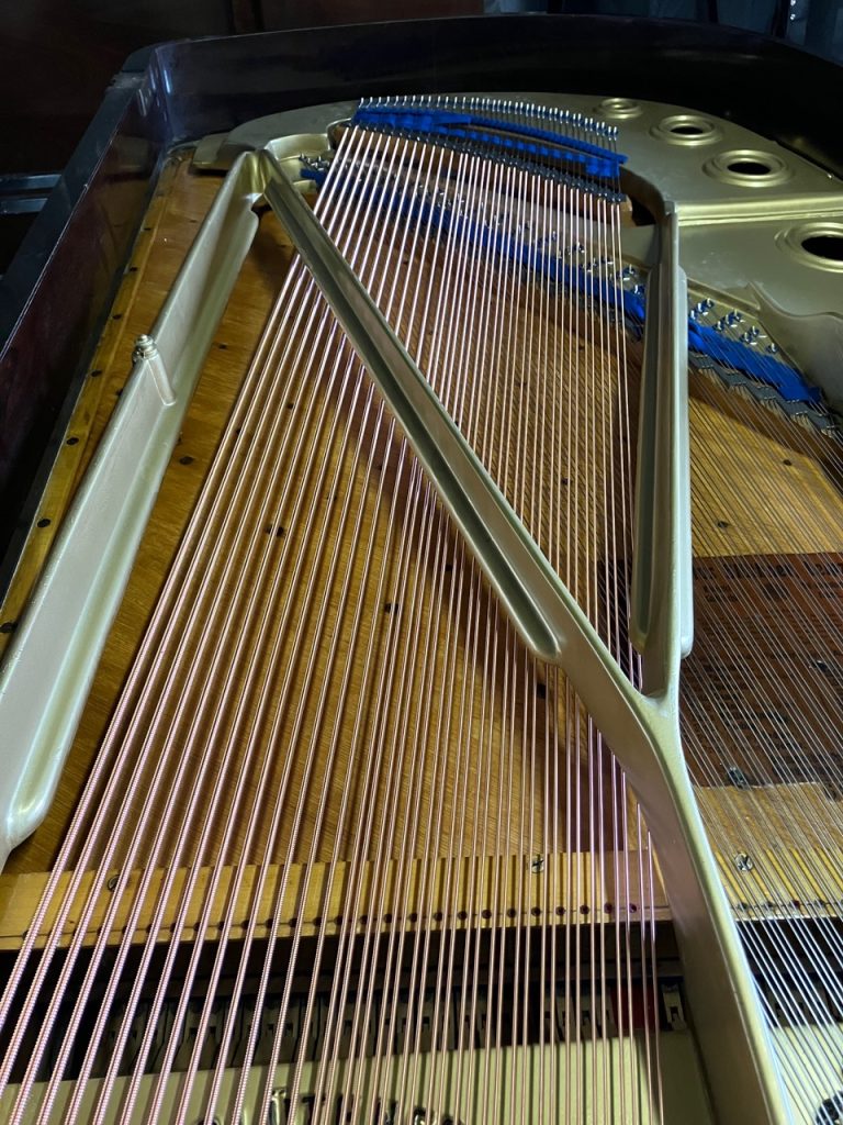 Inside of a restored Bluthner grand piano showing the frame and new strings
