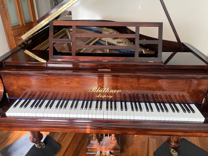 Restored Blüthner grand piano with lid open, keyboard and music desk